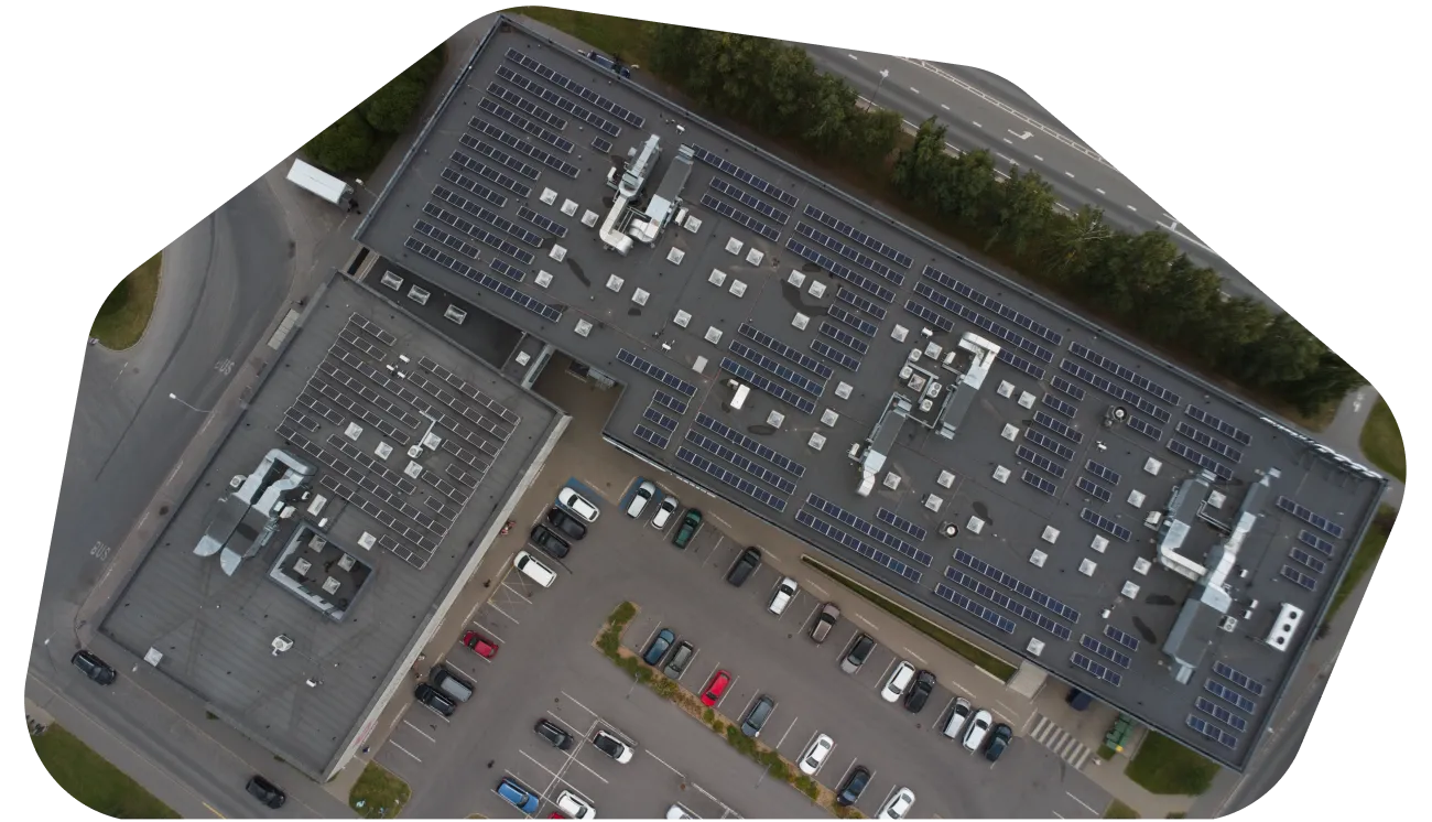 Aerial view of a flat industrial roof with solar panels and skylights